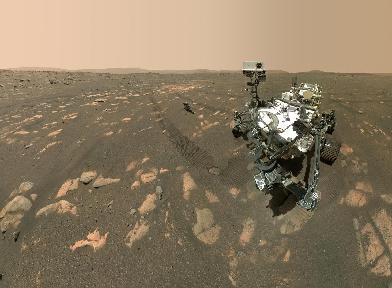 Ingenuity helicopter on the Martian surface with the Perseverance rover visible nearby